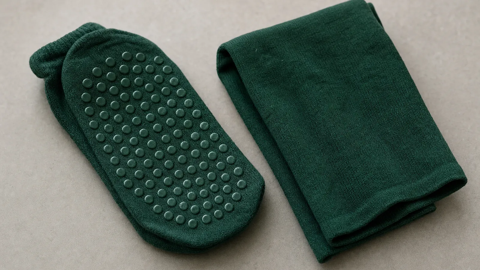 Nahaufnahme der Noppensohle einer grünen Grip-Socke neben einer Tube-Stutze in derselben Farbe.